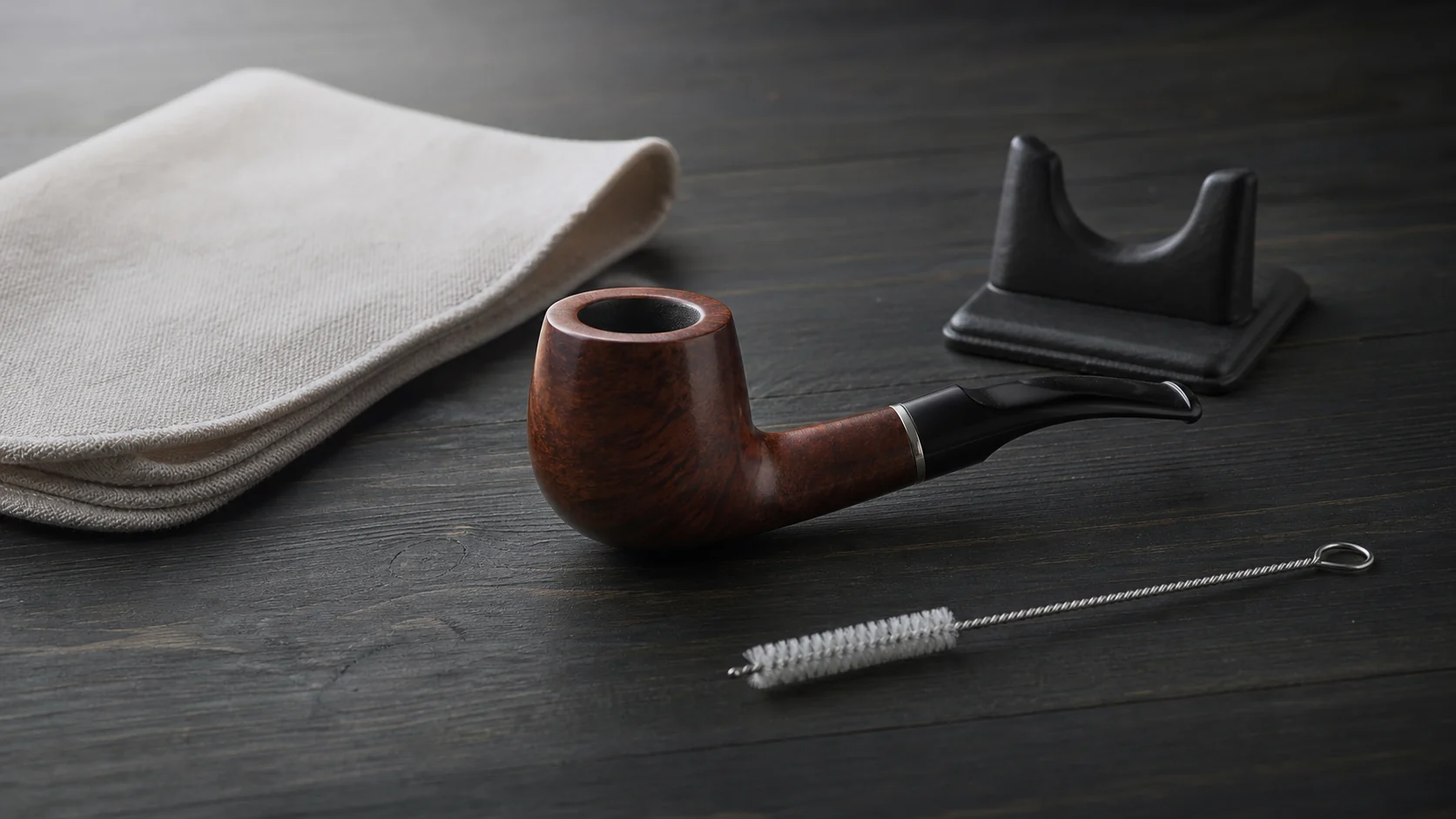 Generic unlit briar pipe arranged with simple storage and care items